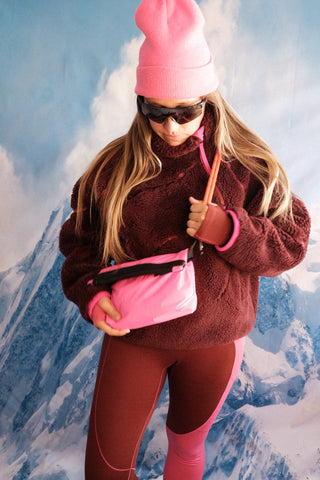 SENIQ model Tina wears Half Baked Fleece Pullover in Moody with Cabin Fever Merino Wool Leggings for insulated warm weather gear that's cozy and vibrant for ski snowboard outerwear with Packbags Crossbody.