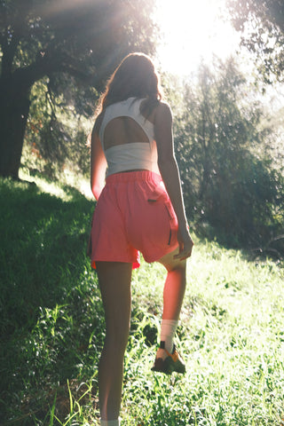 Woman in the woods wearing SENIQ Trailmix Short and Oasis Tank