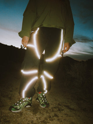 Woman wearing reflective outdoor technical apparel by SENIQ. Dirtpop Trek Jacket andTectonic Pant. Performance apparel no matter the time of day. 