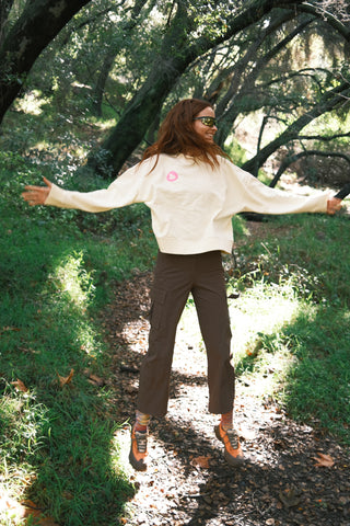 Woman jumping outdoors wearing SENIQ Detour French Terry Sweatshirt with Trailmix Pants