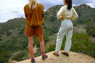 Women overlooking mountain standing on boulder wearing SENIQ Technical Outdoor Clothing