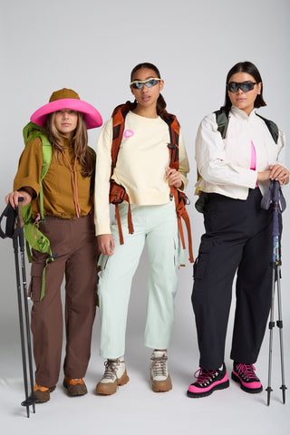 Women in outdoor technical gear designed by SENIQ. Trailmix Reversible Sunhat, Dirtpop Trek Jacket, Trailmix Pants, Detour Sweatshirt